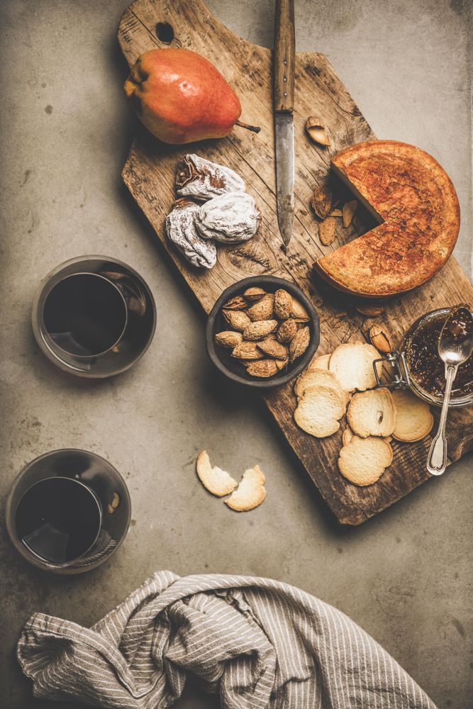 Cheese plate with glasses of red wine, and linen towel on concrete