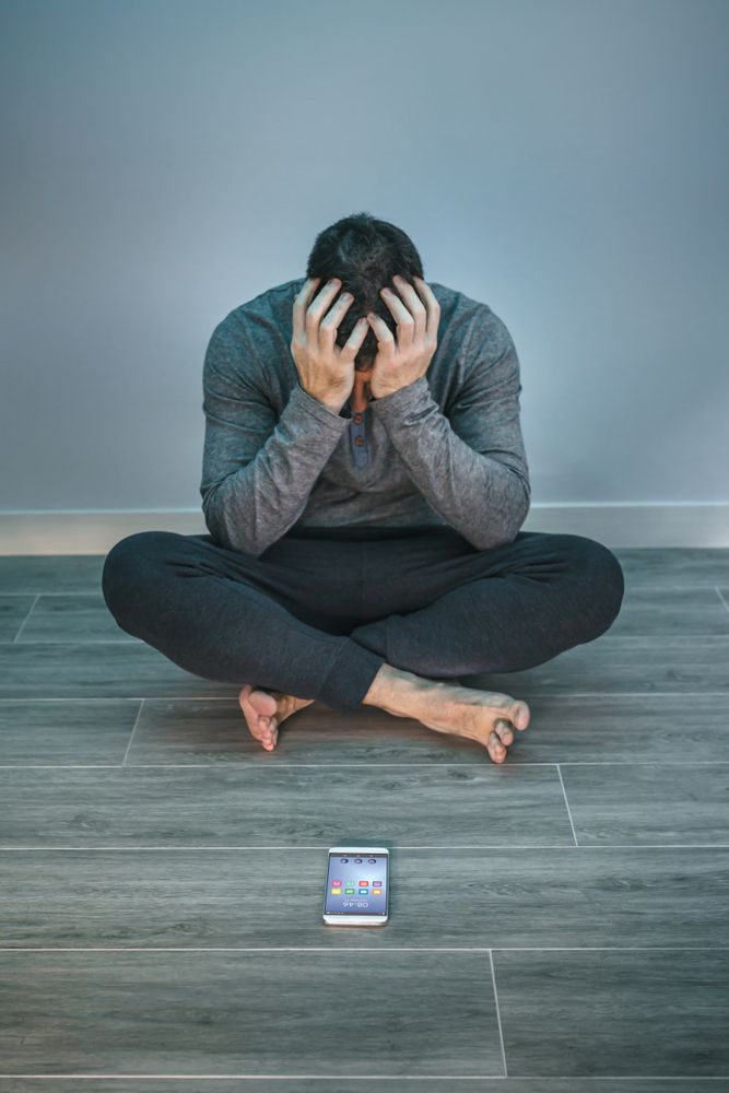 Man with problems sitting on the floor behind of his mobile