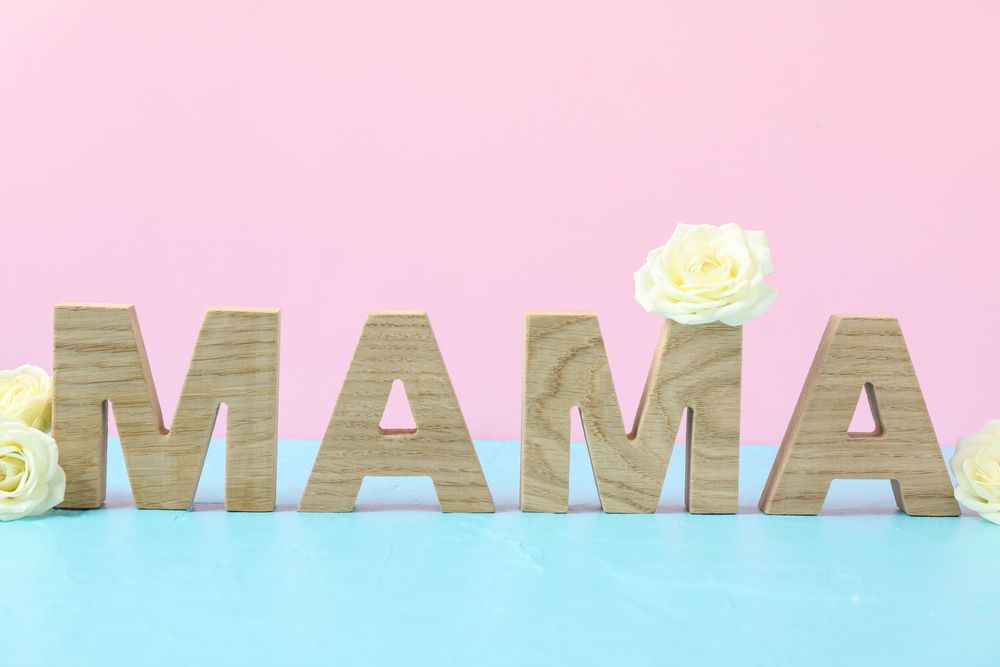 Inscription Mom with roses on blue table against color background, space for text