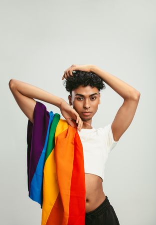 Man with a pride flag posing on light background