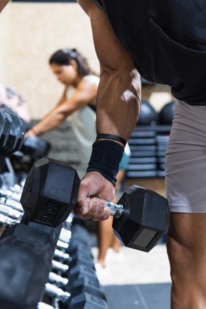 Anonymous sportsman near dumbbells weight set