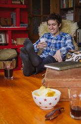 Young man laughing and looking smartphone sitting on chair