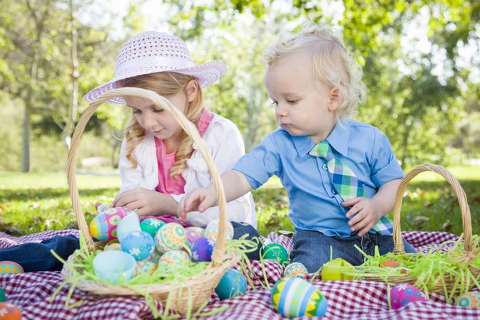 Cute Young Brother and Sister Enjoying Their Easter Eggs Outside