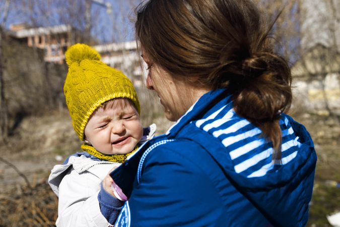 Woman holding her crying child outside