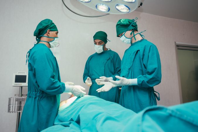 Three surgeons over patient in operating theater preparing for surgery