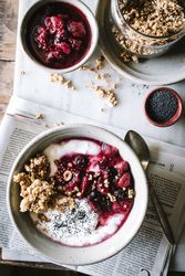Delicious breakfast bowl with quinoa, rice and groats near tea cup and newspaper