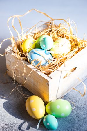 Easter holiday concept with crate of pastel eggs in straw