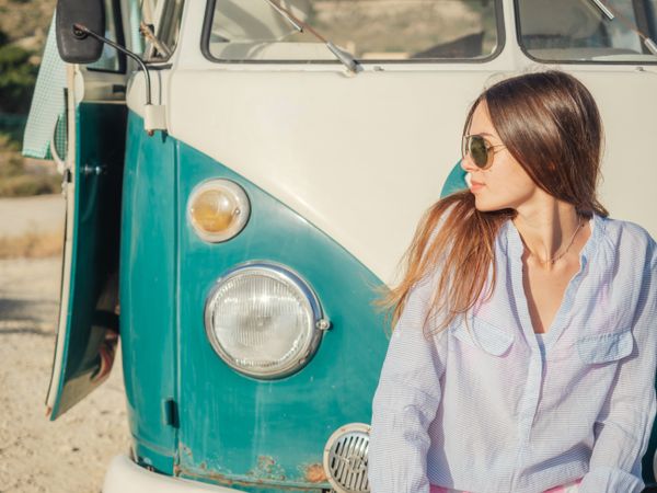 Woman sitting on bumper of car