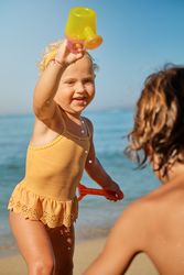 Charming girl in yellow swimsuit having fun with watering can