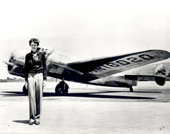 Amelia Earhart standing in front of the Lockheed Electra in which she disappeared