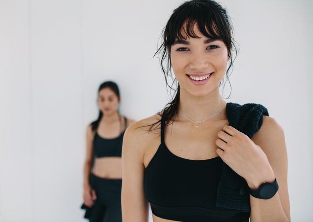 Close up portrait of smiling sportswoman in gym with female friend in background