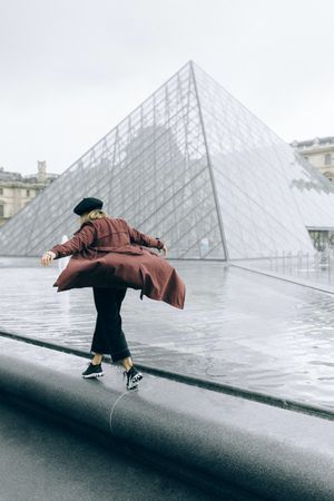 Woman walking beside Louvre museum's glass pyramid