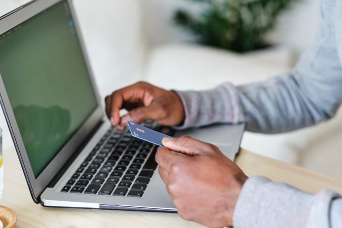 Crop Black shopper with credit card and laptop at home