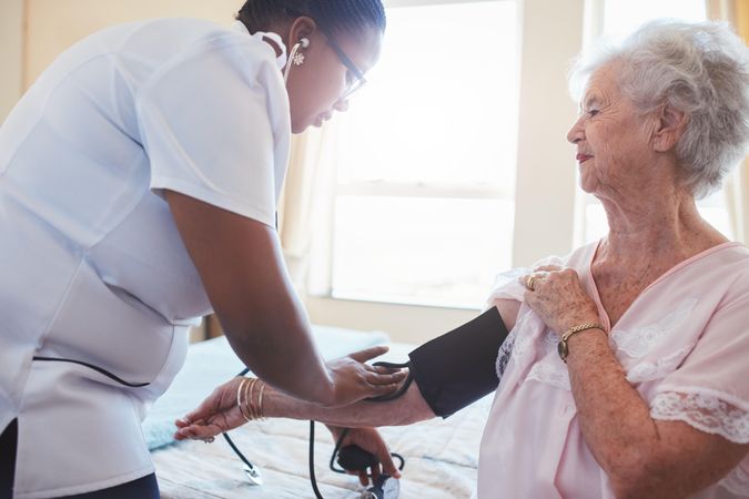 Home nurse doing blood pressure measurement of a mature patient