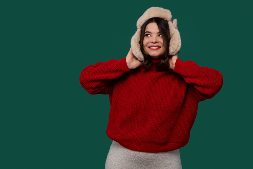 Happy woman in red sweater adjusting fluffy fur hat