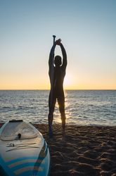 Man practicing paddle surfing with neoprene in a sunrise