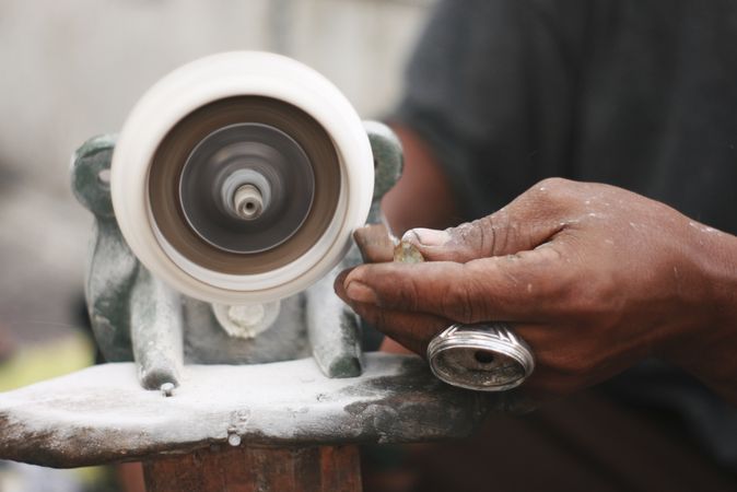 Hands shaping agate stone on grinder wheel