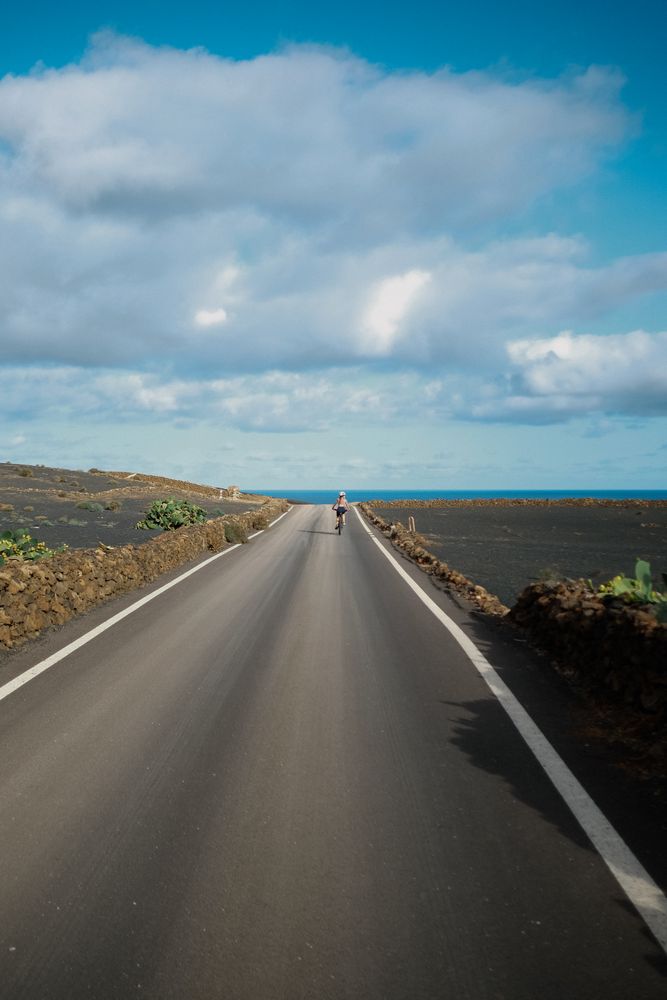 Back of female biking on Lanzarote paved road
