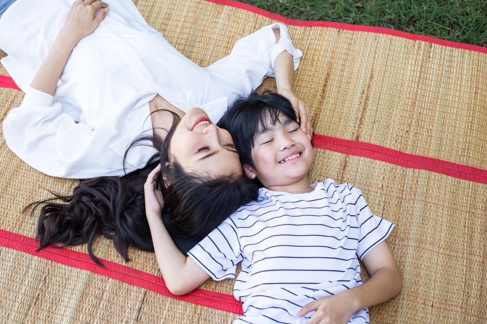 Mother and child laying on picnic throw on grass