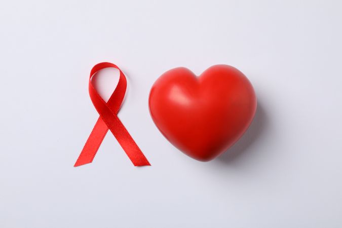 AIDS awareness red ribbon and heart on blank background, space for text