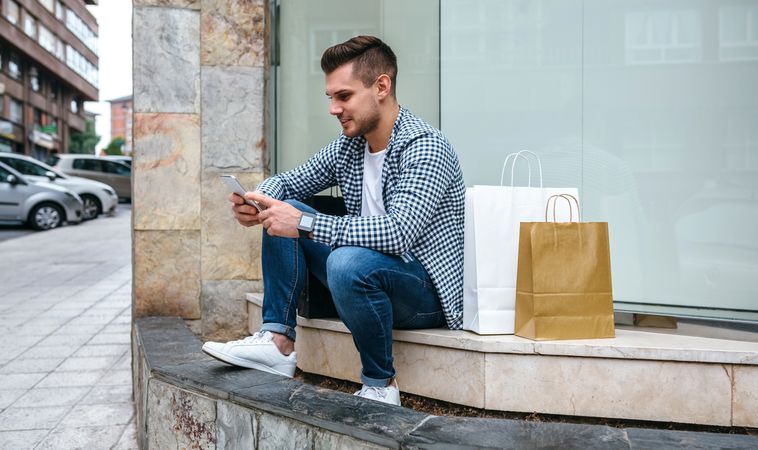 Young man with shopping bags sitting