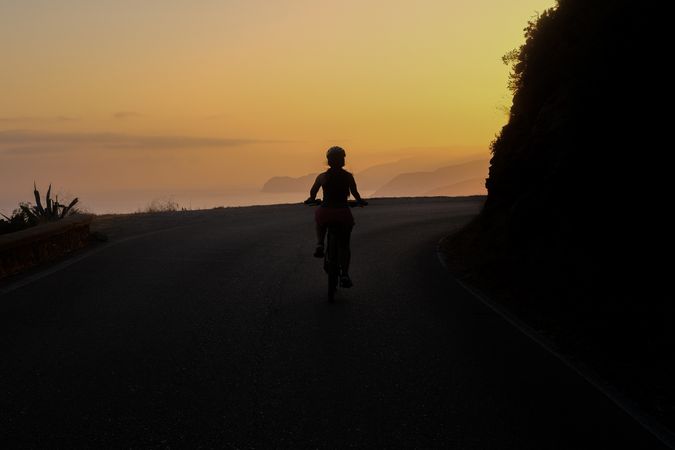 Silhouette of an biking along coast at sunset