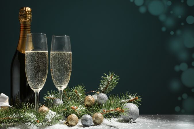 Champagne glasses and bottle on decorated background, space for text