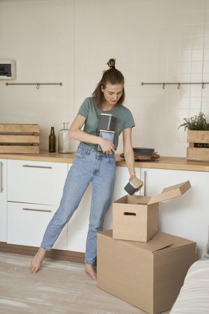 Careful woman holding containers with hand and taking cans out of box