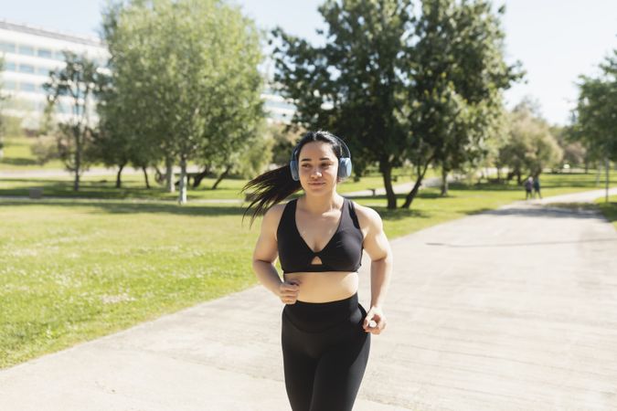 A young woman running outdoors, happy, while listening to music with headphones, Zaragoza, Spain
