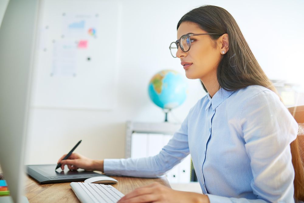 Female graphic designer writing on stylus on digital pad in her office