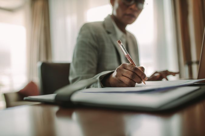 Businesswoman sitting at hotel room desk writing on document