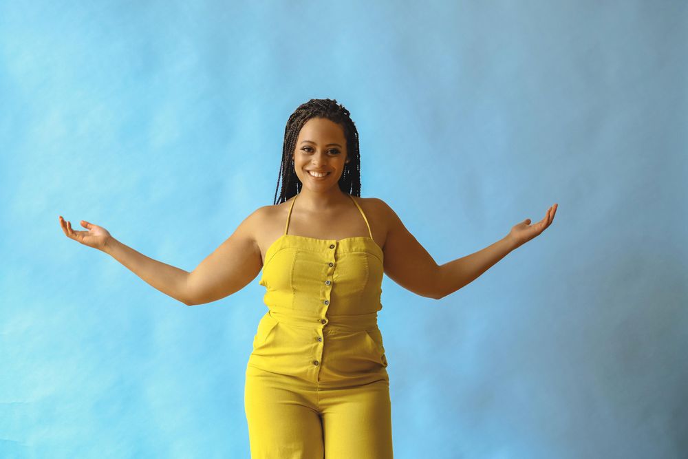 Female with long braided hair and open arms in yellow one piece
