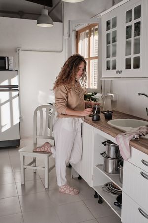Young woman preparing coffee in kitchen