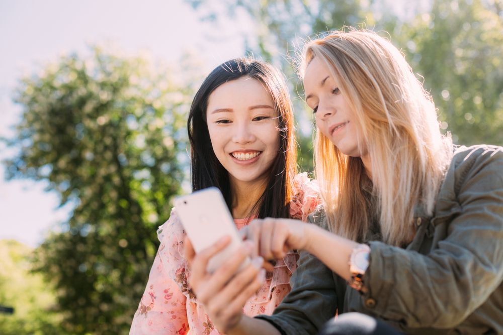 Female friends using smartphone in park