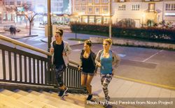 Fit female friends training running up stairs in city at night 5lVmWY