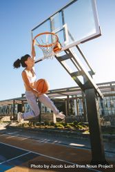 Woman slam dunking basketball 5pqoe4