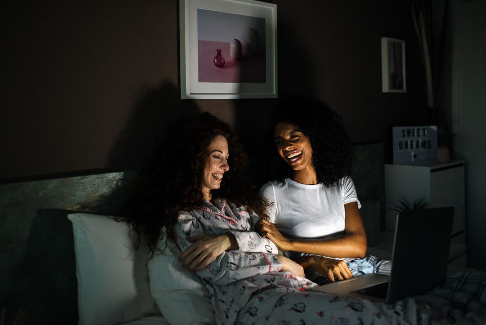 friends in bed entertained on their computer