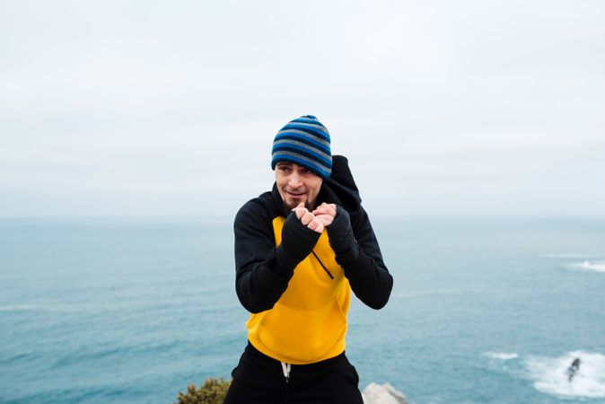 Kickboxer training on cliff near sea