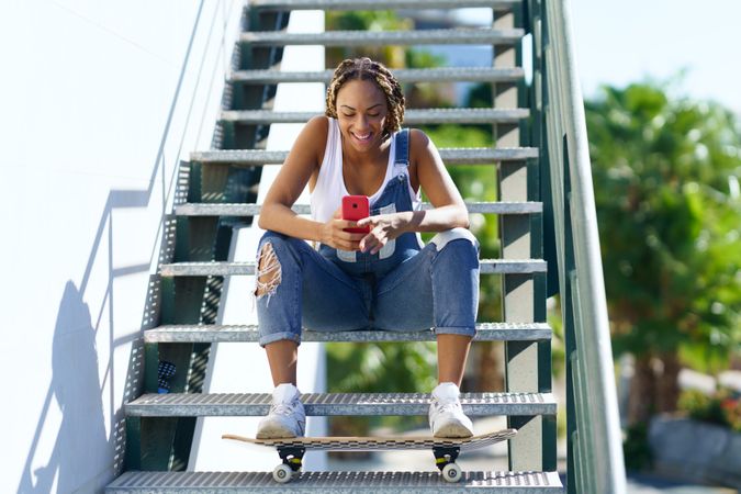 Happy female resting on stairs with skateboard