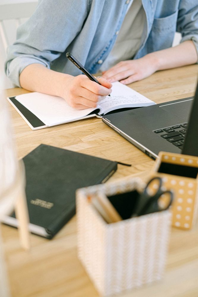 Man writing a note on note book sitting at desk
