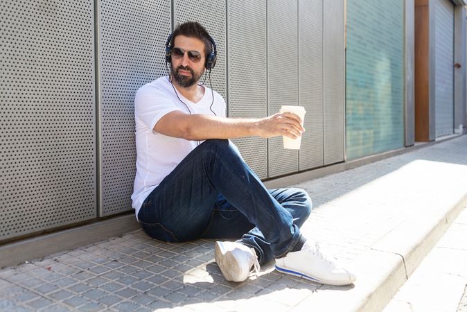 Man sitting on pavement outside with coffee