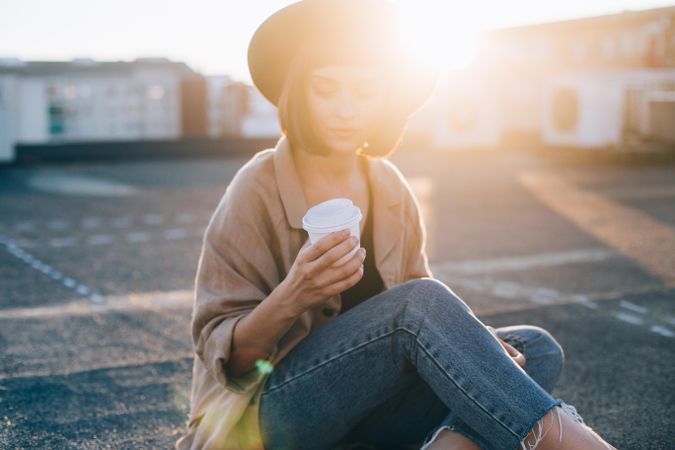 Backlit woman sitting outside with coffee