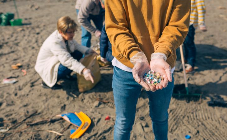 Hands with microplastics on the beach