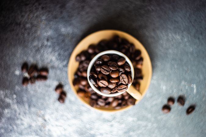 Top view of espresso cup full of coffee beans on grey counter