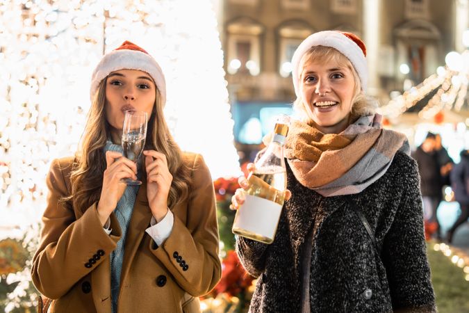 Three happy friends taking a selfie at a Christmas market at night.