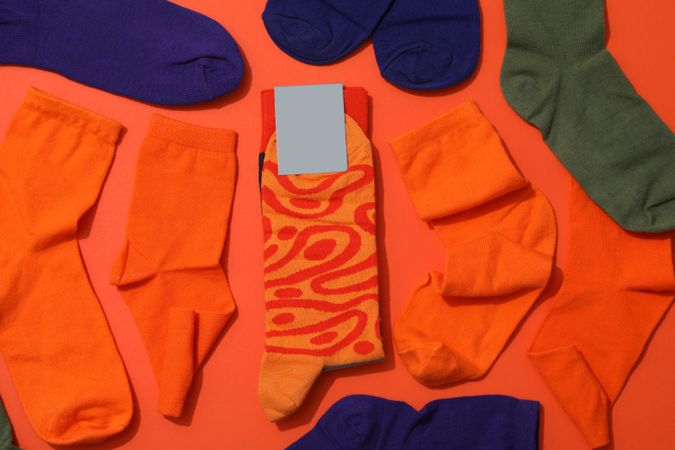 Bright socks with a print, in a pile on an orange background.