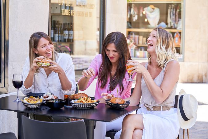 Cheerful female friends enjoying lunch in outdoor cafe