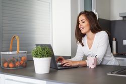 Smiling woman browsing on laptop and sitting on settee