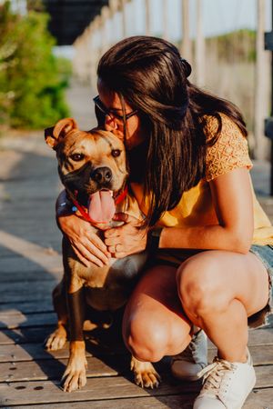 Happy adult woman hugging dog at countryside