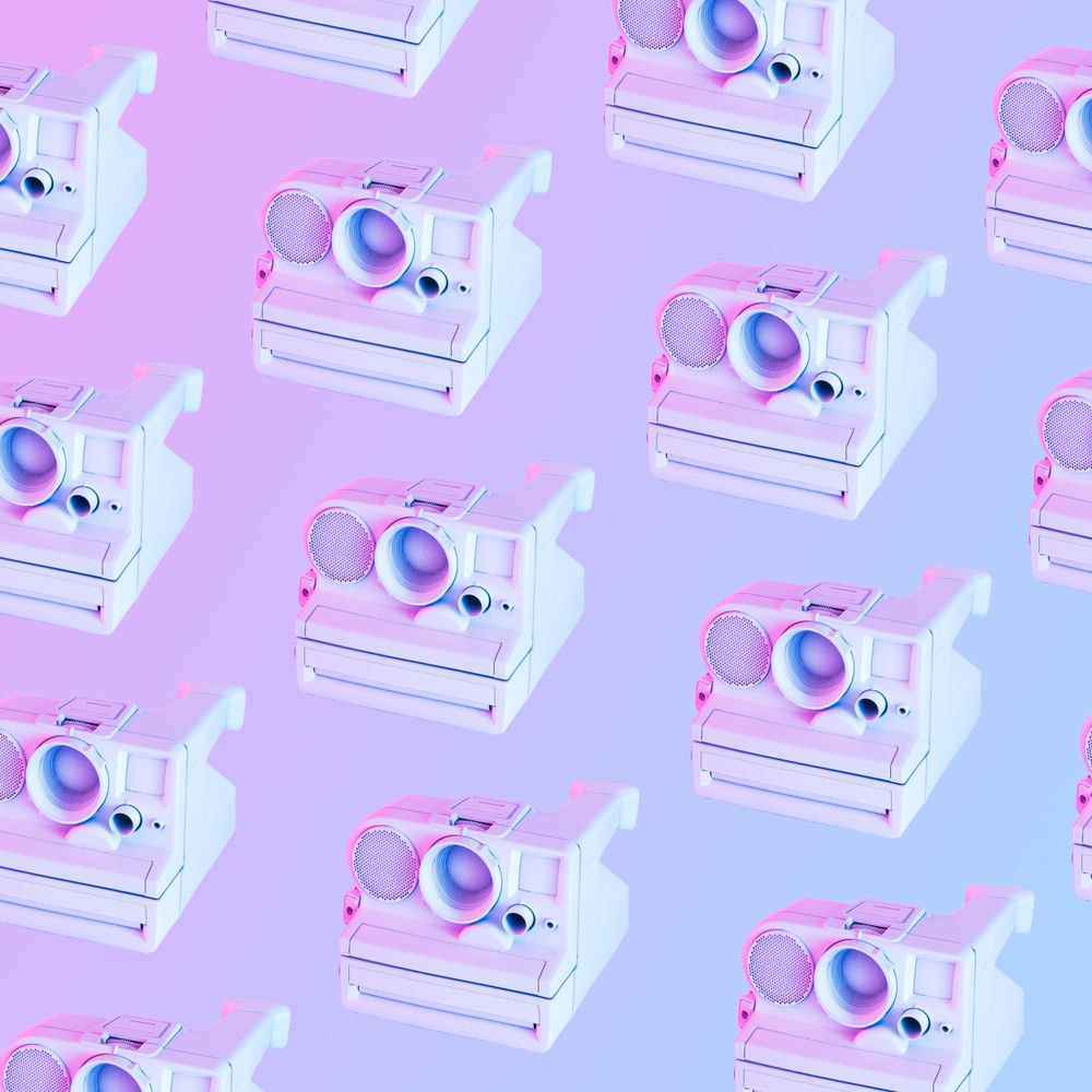 Pattern of vintage camera in light colored paint and with vibrant holograph